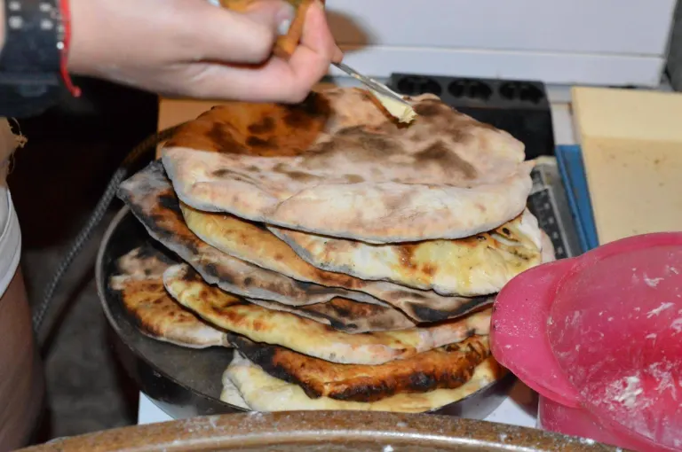 Butter being spread on a stack of freshly baked flatbreads