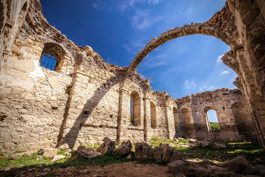 Roofless arches of an old stone church under a blue sky