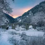 Old stone bridge in a snowy Rhodope valley at dusk