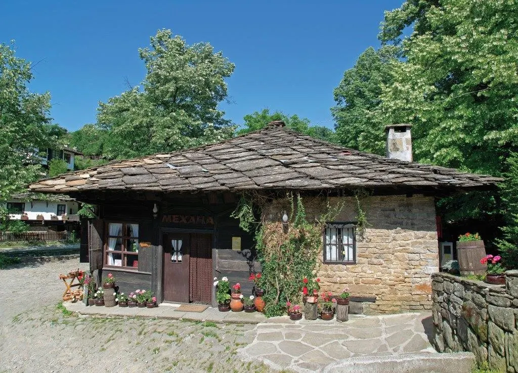 Small stone house with a stone-slab roof and flowers by the door